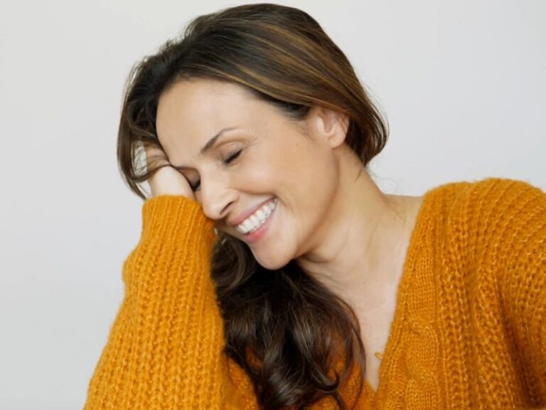 žena srednjih godina dira svoju kosu i veselo se smeši