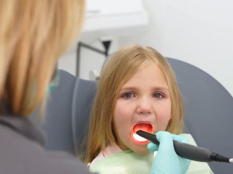 devojčica sedi na stolici kod stomatologa na pregledu